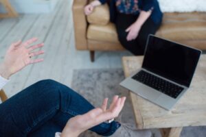 Two people sit comfortably across from one another in a rustic-chic office space, discussing content development in front of an opened laptop.