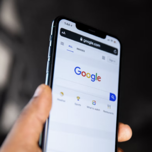 Image of a hand holding an iphone with the Google search page displayed