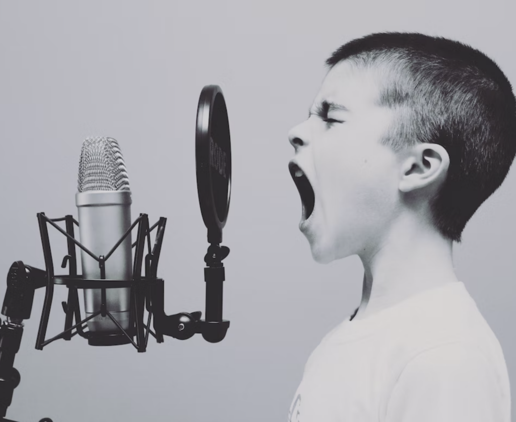 Black and white profile image of a boy screaming into a microphone