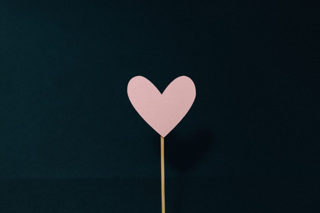 black background with pink heart in the middle on a stick